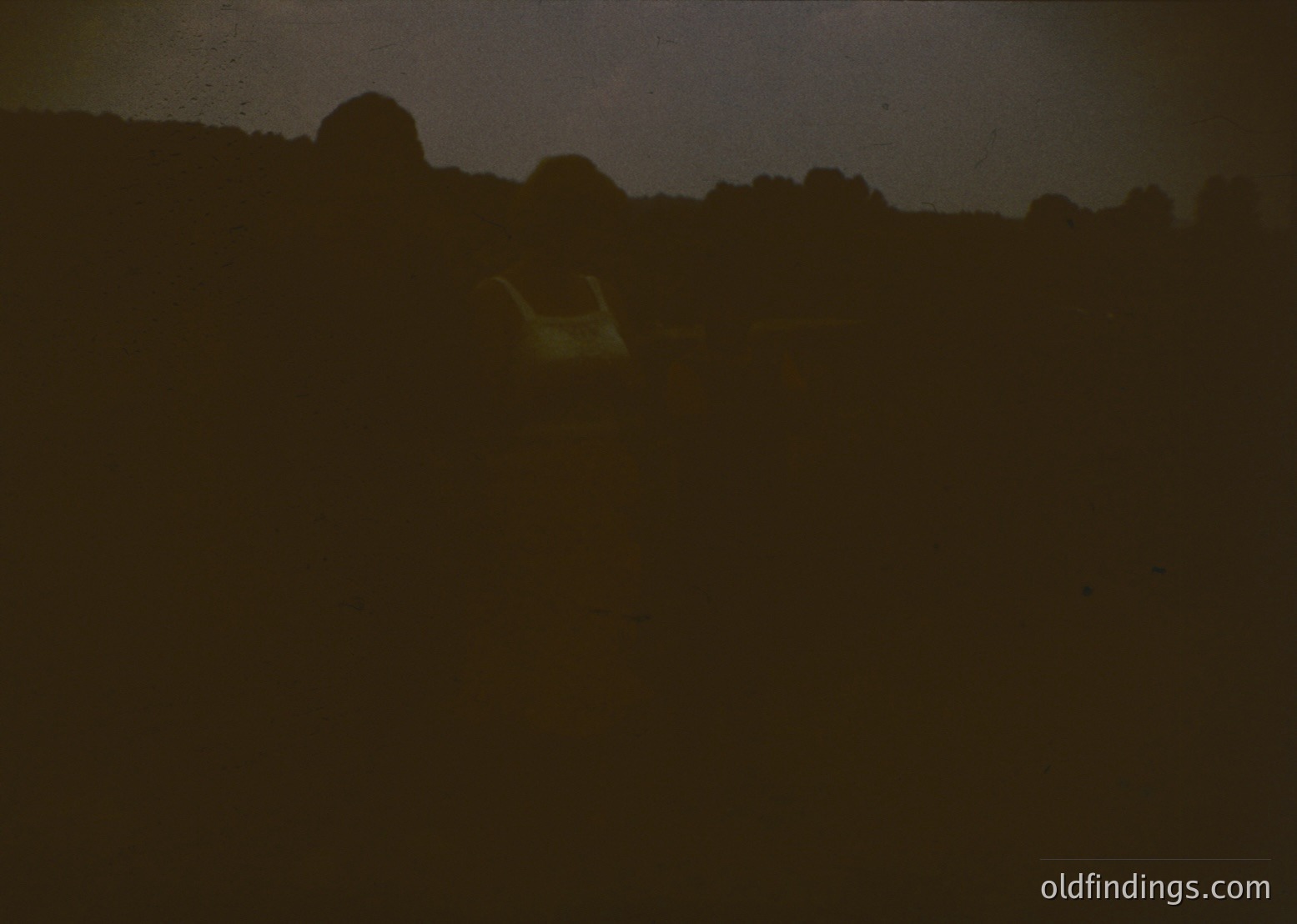 Low-contrast silhouette of silhouetted figures in a wooded area, backlit by sunlight. Likely a group of people walking or standing. Undefined location but suggests forest or park setting. Potential use for mood/atmospheric stock imagery.