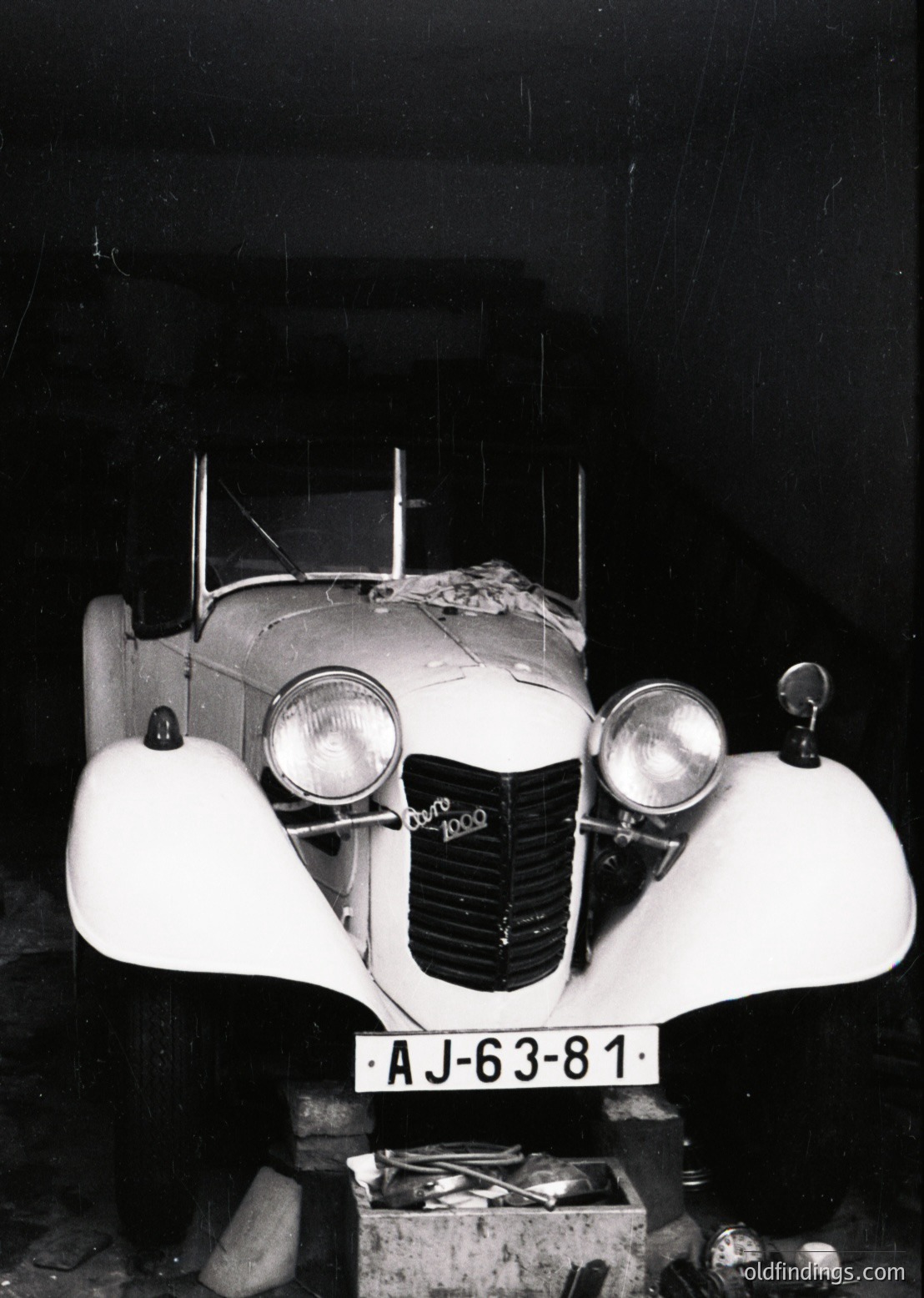 Classic 1930s–1940s **Alfa Romeo 6C 1500** convertible, captured in dim indoor lighting. Distinctive streamlined bodywork, dual round headlamps, and "Alfa Romeo" script on the grille. License plate "AJ-63-81" suggests European registration. Ideal for vintage automotive archives or design inspiration.