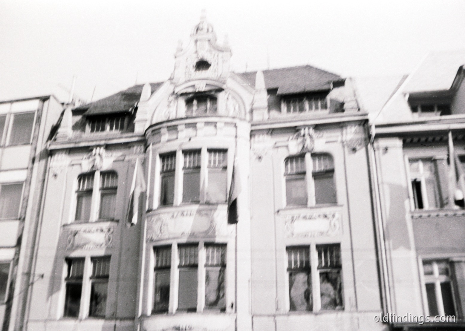 Art Deco-inspired corner building with ornate gables, decorative stonework, and symmetrical windows—likely early 20th century. Weathered facade suggests mid-century urban architecture.