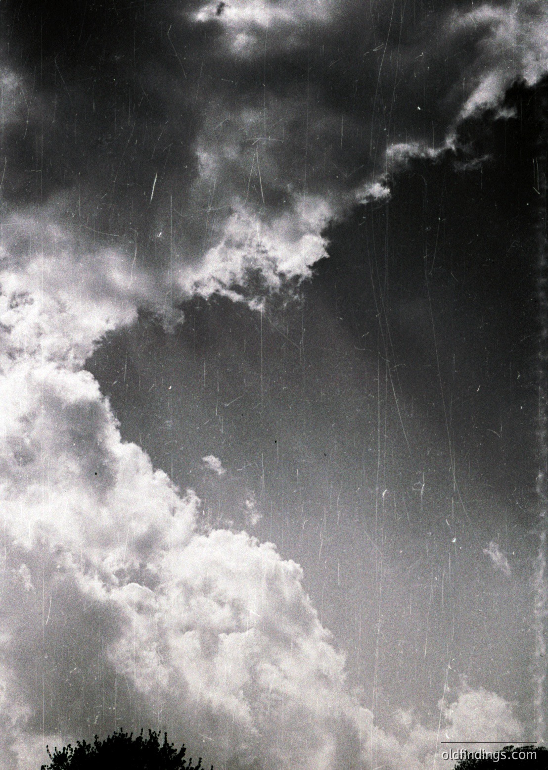 Dramatic monochrome sky with dense cumulus clouds and vertical rain streaks, suggesting impending storm. High-contrast lighting captures dynamic cloud formations and raindrops in motion.