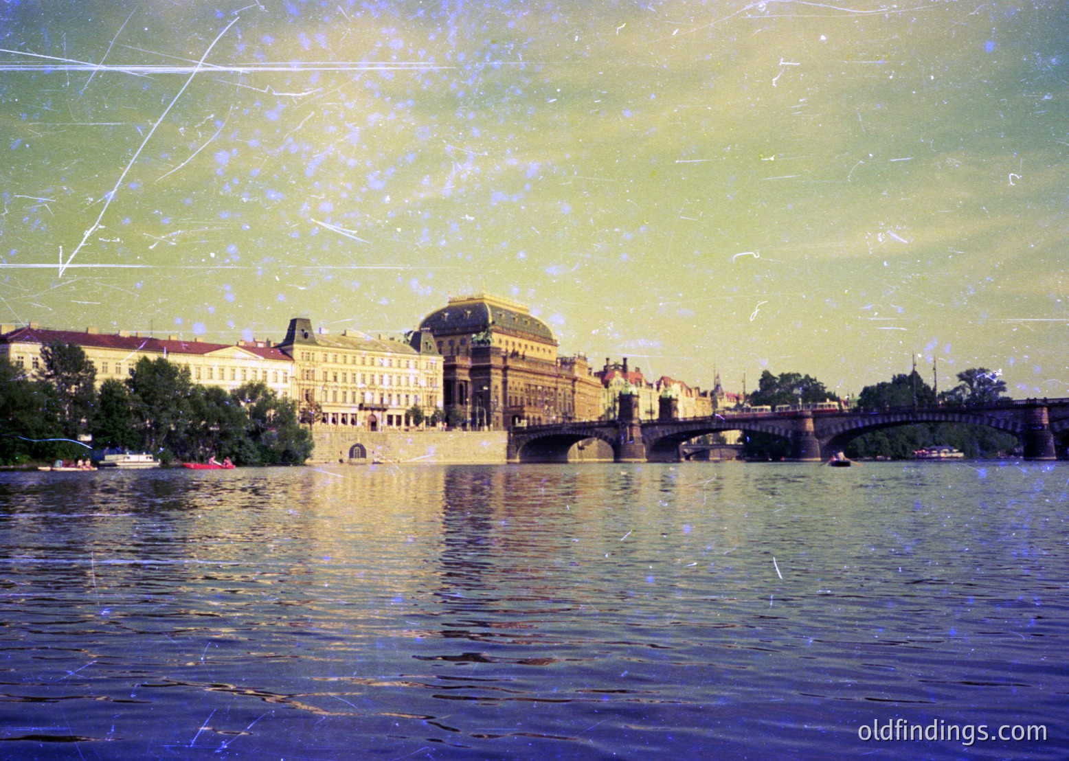 Vintage sepia-toned photograph of Prague’s **Charles Bridge** with **St. Nicholas Church** in background. Reflective water captures historic Baroque architecture and bridge arches. Light streaks suggest motion blur from passing boats. *(Note: Exact time period is speculative but likely late 1800s–early 1900s based on style.)*