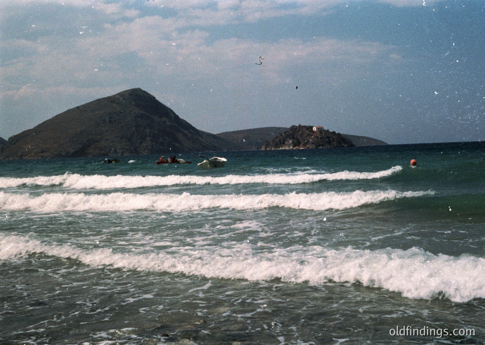 Vintage coastal scene featuring surfers riding waves near a rocky island formation. Mid-20th century beach culture with vintage color tones. Waves crash against shallow waters, and a lone surfer in a red buoy waits offshore.