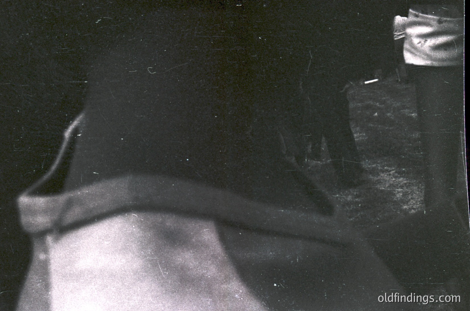 Vintage black-and-white close-up of a **hand holding a cigarette** in a **smoking jacket sleeve**, suggesting mid-20th century leisure. Dark, grainy texture hints at early film photography. Ideal for historical research on smoking culture or fashion.