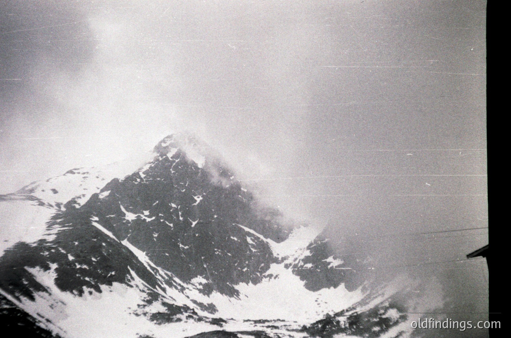 Classic aerial view of a snow-capped alpine peak shrouded in mist, likely the Matterhorn. Black-and-white composition highlights dramatic rock formations and glaciers.