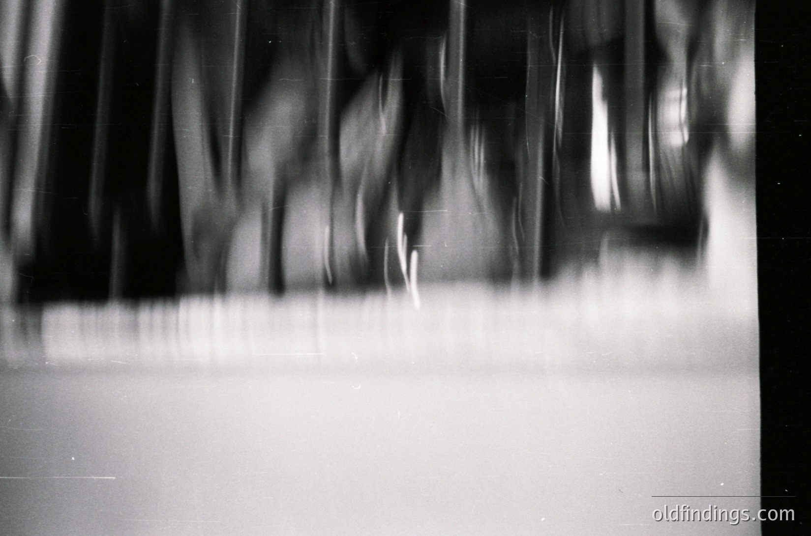 Blurred motion photography capturing dynamic movement in monochrome. Vertical streaks suggest rapid, repetitive action—likely dancers or performers in a studio or theater. Artistic use of long exposure highlights energy and rhythm. Ideal for abstract design, motion studies, or visual storytelling.