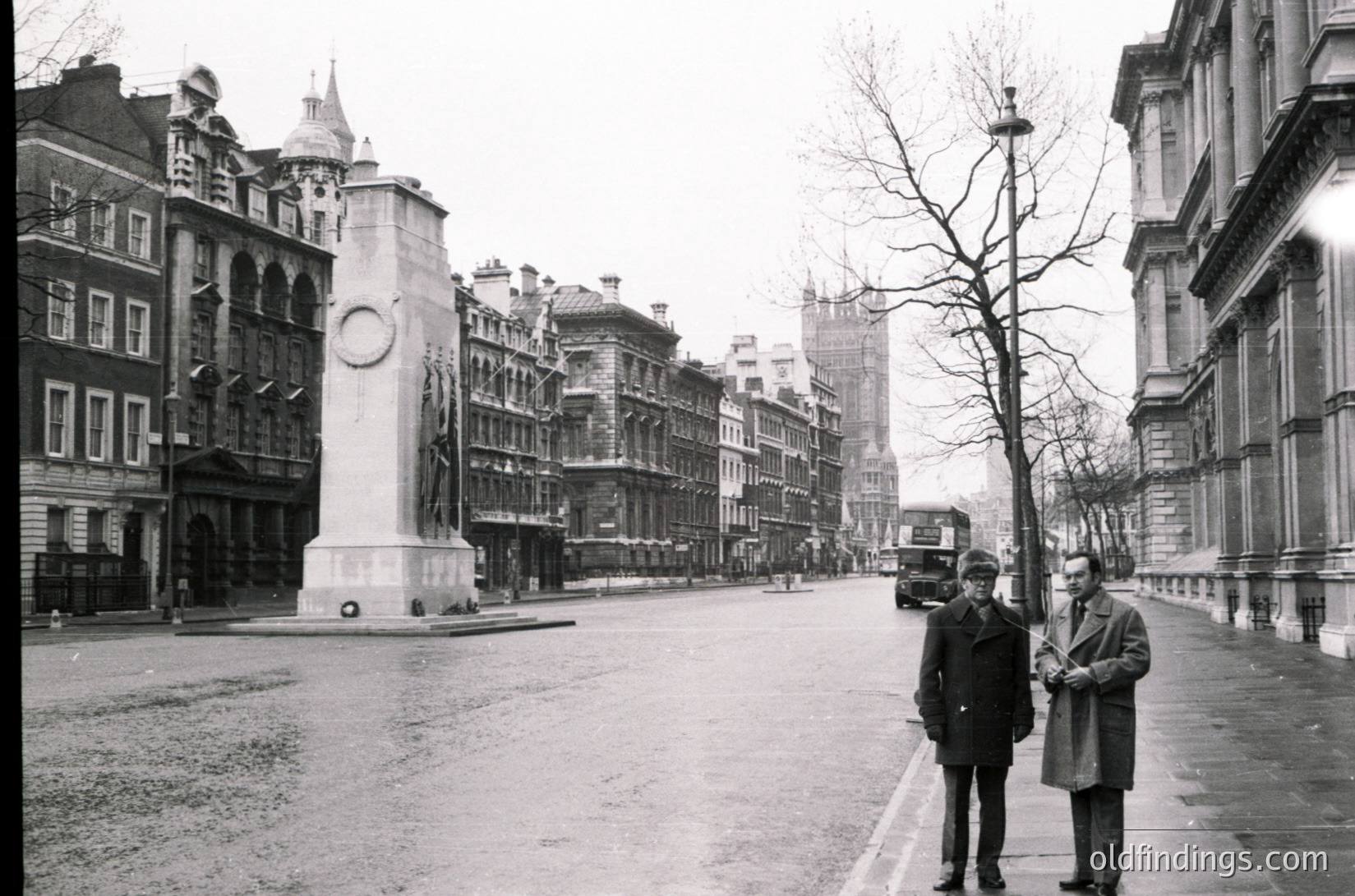 Where is this: two men in 1950s-era suits stand near Nelson’s Column in London’s Trafalgar Square