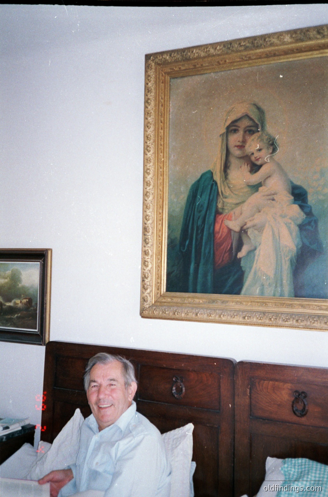 Classic religious portrait of Madonna and Child in ornate gilded frame, 19th-century European style. Elderly man seated at vintage wooden desk with brass handles, holding papers. Interior suggests mid-20th century domestic setting. écor