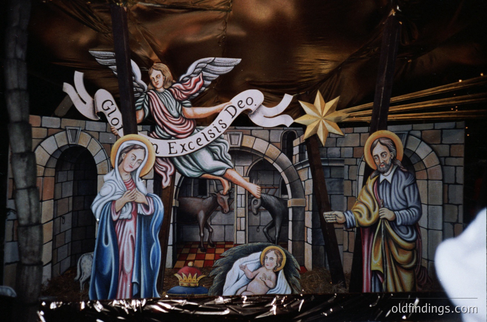 Religious nativity mural depicting Christ’s birth: angel announces *"God Excelsis Deo"* (Luke 2:11), Mary cradles infant Jesus, Joseph kneels, and ox/enfant figures below. Stone arch framing suggests 19th–20th century church interior, likely Eastern Orthodox or Latin Christian tradition.