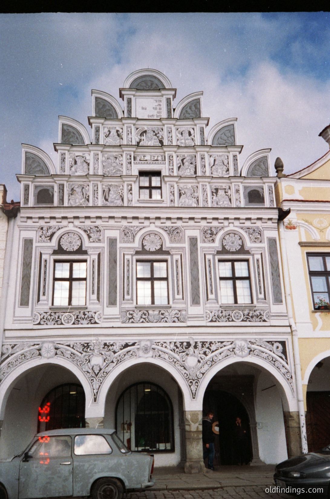 Baroque-style building with intricate stucco detailing, arched ground-floor entrance, and decorative clock tower. Symmetrical facade features ornate moldings, arched windows, and sculpted reliefs. Likely European, possibly or , architecture.