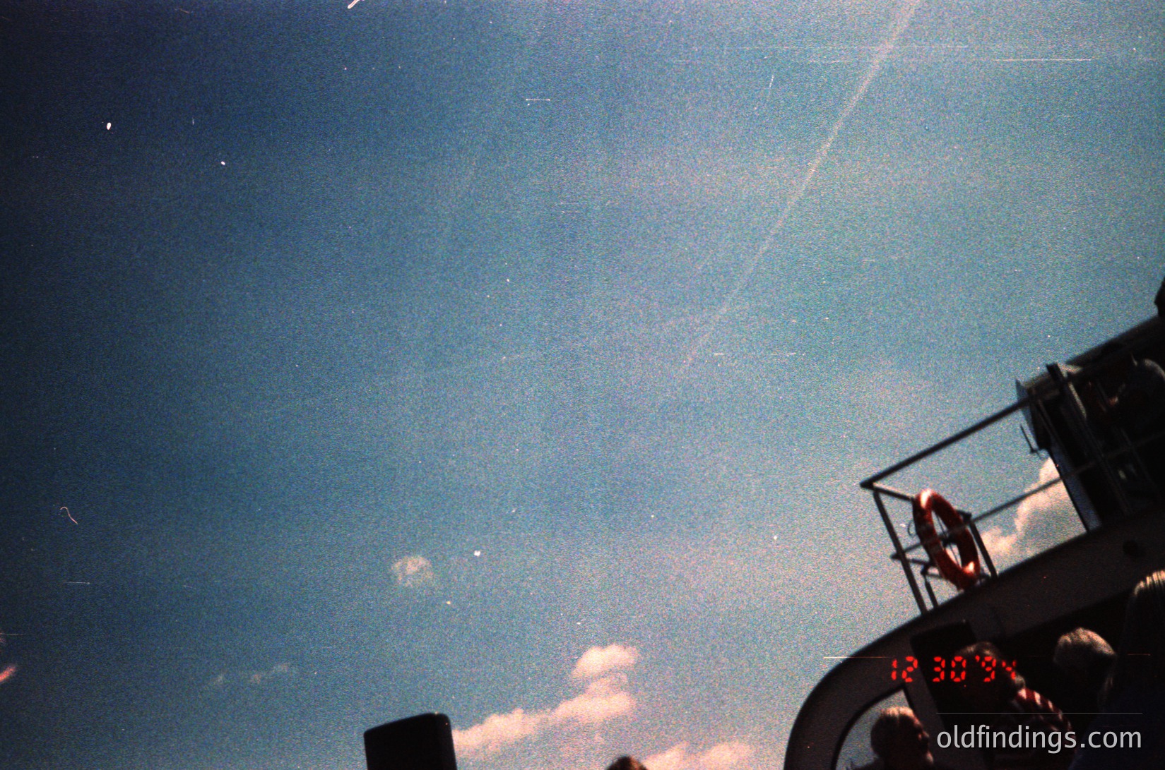 Vintage aerial shot of a clock tower displaying **12:30**, framed by a vintage camera lens. The hazy sky suggests mid-20th-century photography (). Architectural detail hints at urban or industrial setting.