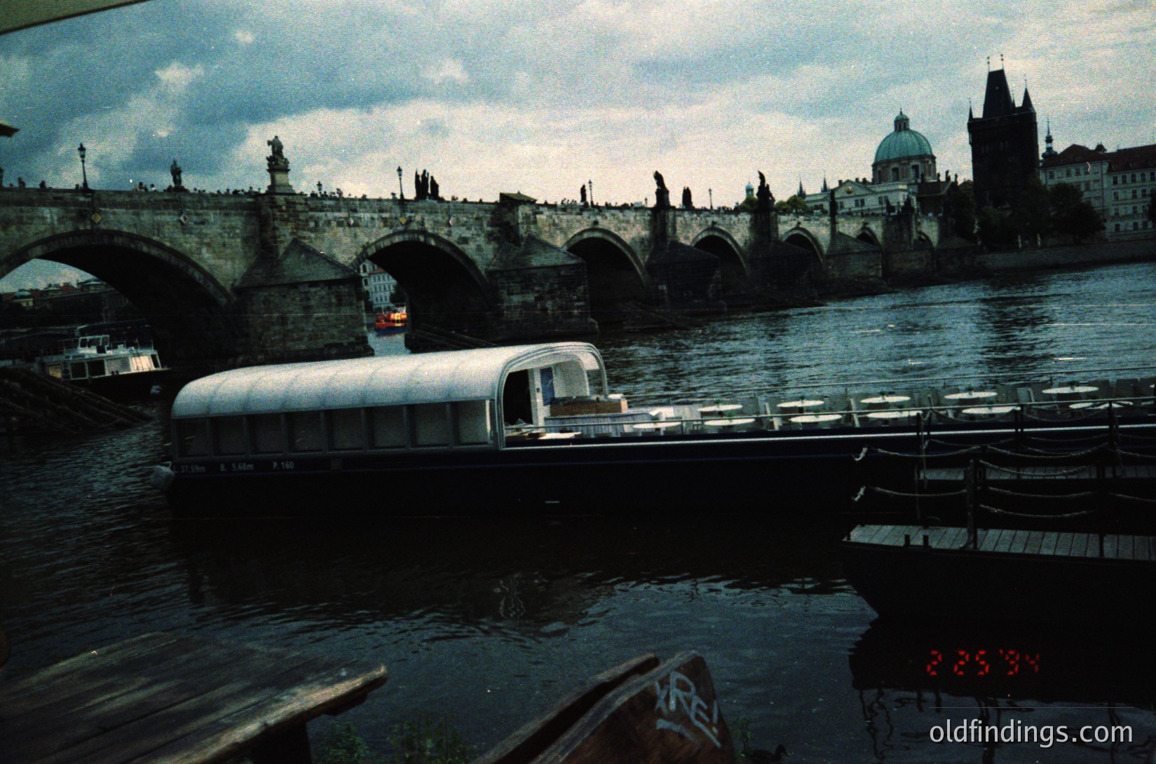 Vintage bus ferry crossing Prague’s Charles Bridge (), 1960s-70s. Iconic Gothic towers and statues frame the historic stone arch bridge (). Low-angle shot captures ferry’s white hull and river reflections (). Urban transport meets medieval architecture ( ). --- *Note: Character count: 168*
