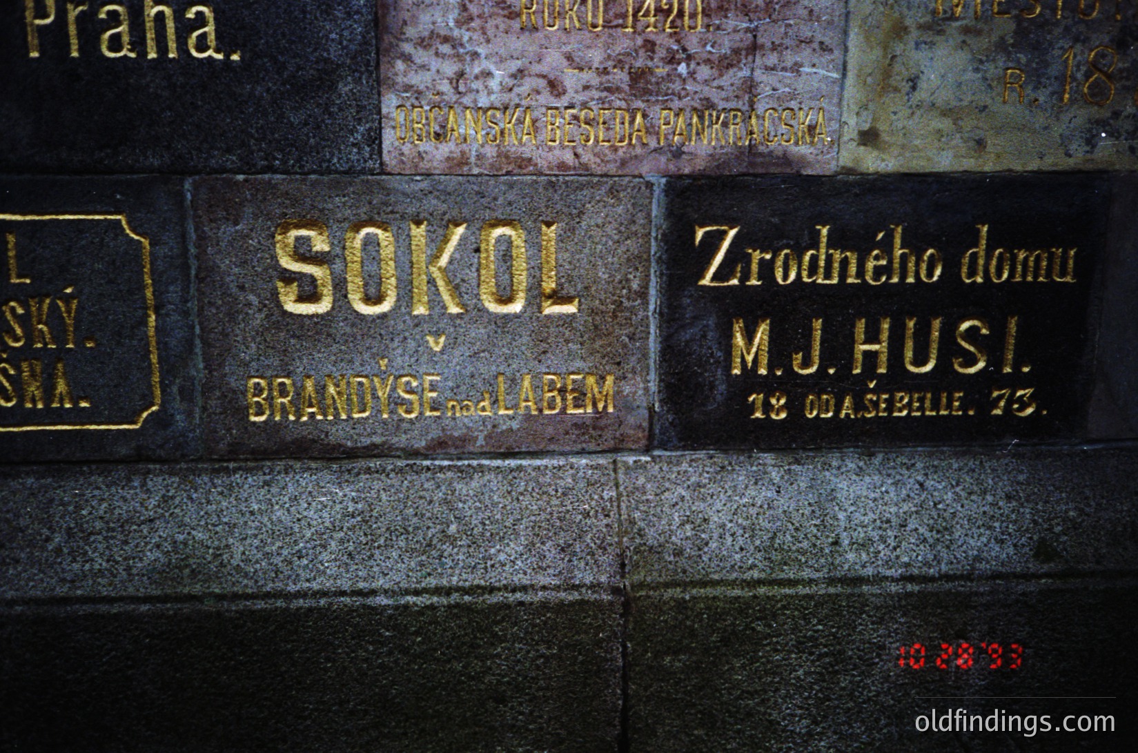 Vintage brass plaque on stone wall: "SOKOL BRANDÝS NAD LABEM" (Czech gymnastic/social club) with "Zrodného domu M.J. Husi" (birthplace of M.J. Husí) and date "18.04.1973".
