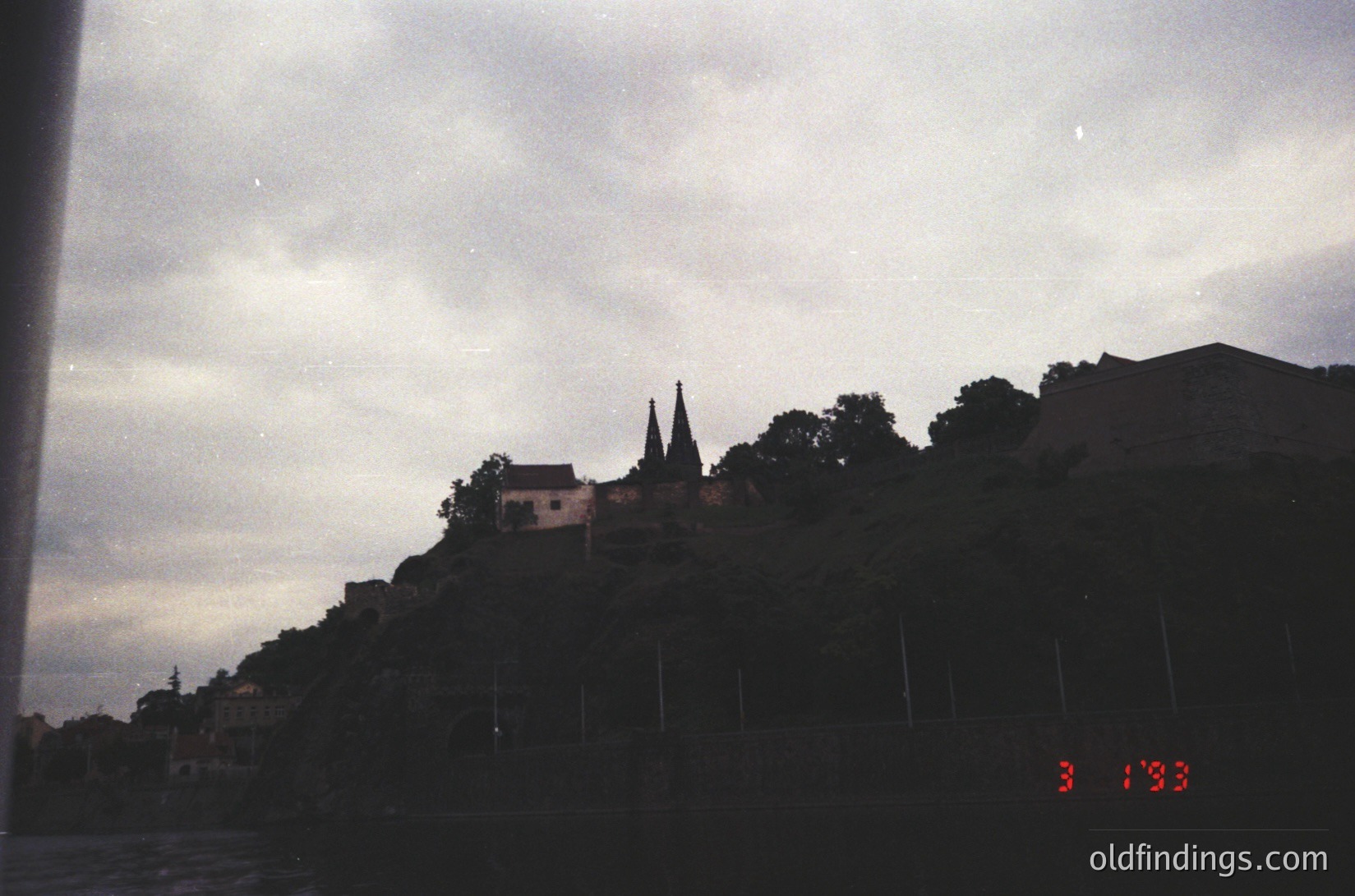 Silhouetted hilltop church with twin spires against dusk sky, framed by low-angle shot. Date stamp "3.1993" suggests early 1990s Eastern European coastal setting. Minimalist composition ideal for historical/architectural research.