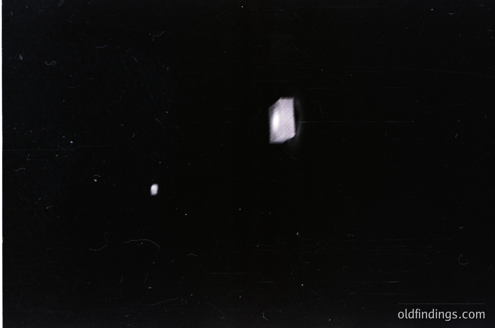 Vintage black-and-white photo of two faint, overexposed light sources against a dark background—likely a moon and planet in night sky. Composition suggests early photography or astronomical documentation.