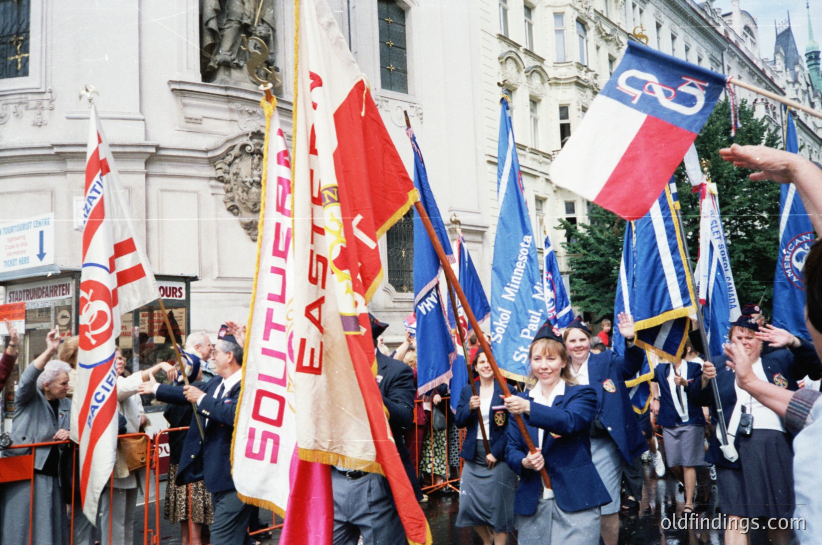 Group of marchers in 1970s-era Southeastern U.S. holding flags for "Southeastern" and "United Blue" with "Southern" text, likely representing labor or regional unity. Classic brick buildings and vintage clothing suggest a mid-century American protest or rally. Crowd appears engaged, with some clapping.