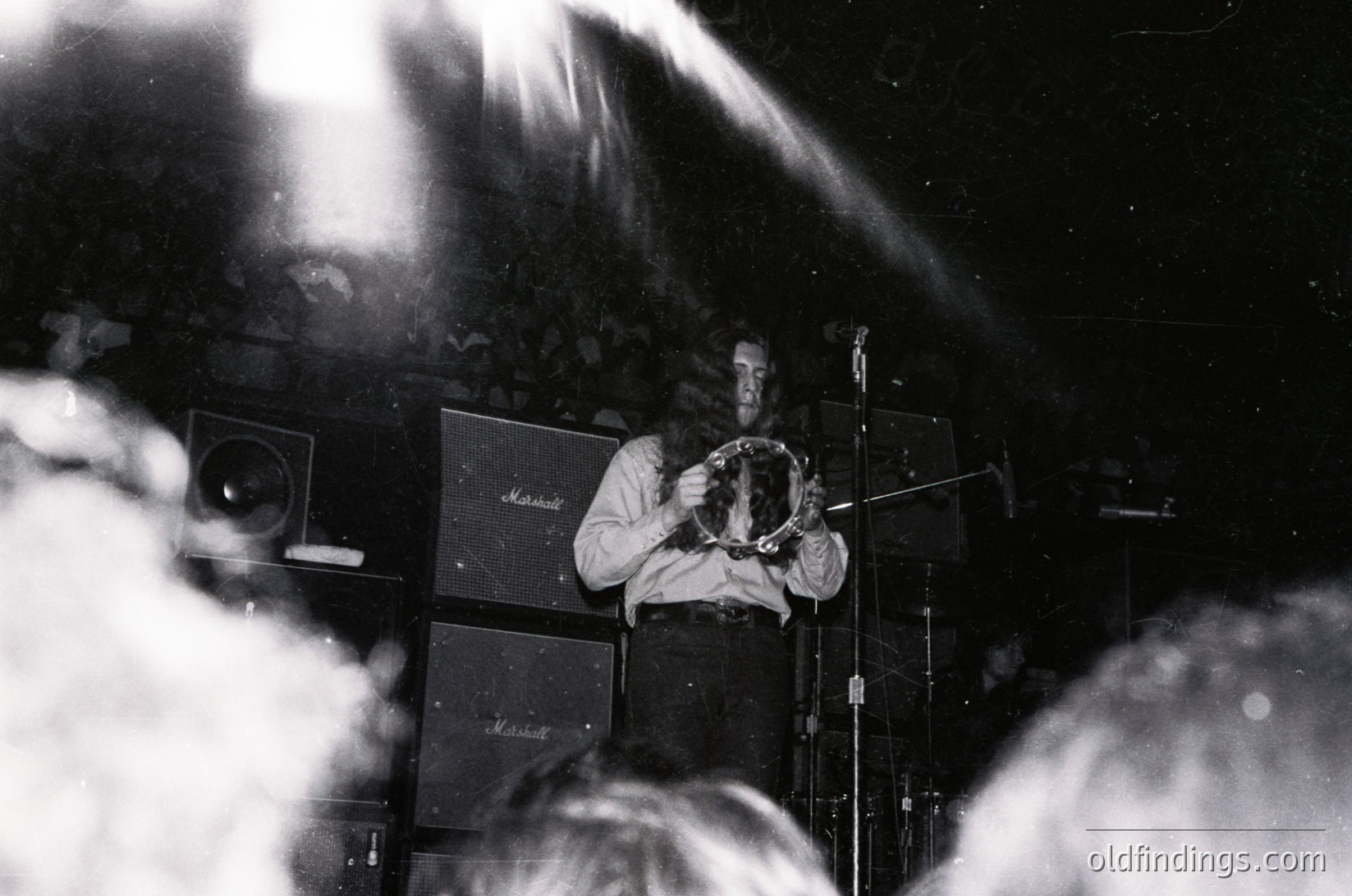 Vintage black-and-white photo of a musician playing a Marshall stack amplifier, likely a **Jimi Hendrix** tribute or 1960s-70s rock concert. Stage lighting creates dramatic shadows and smoke haze.