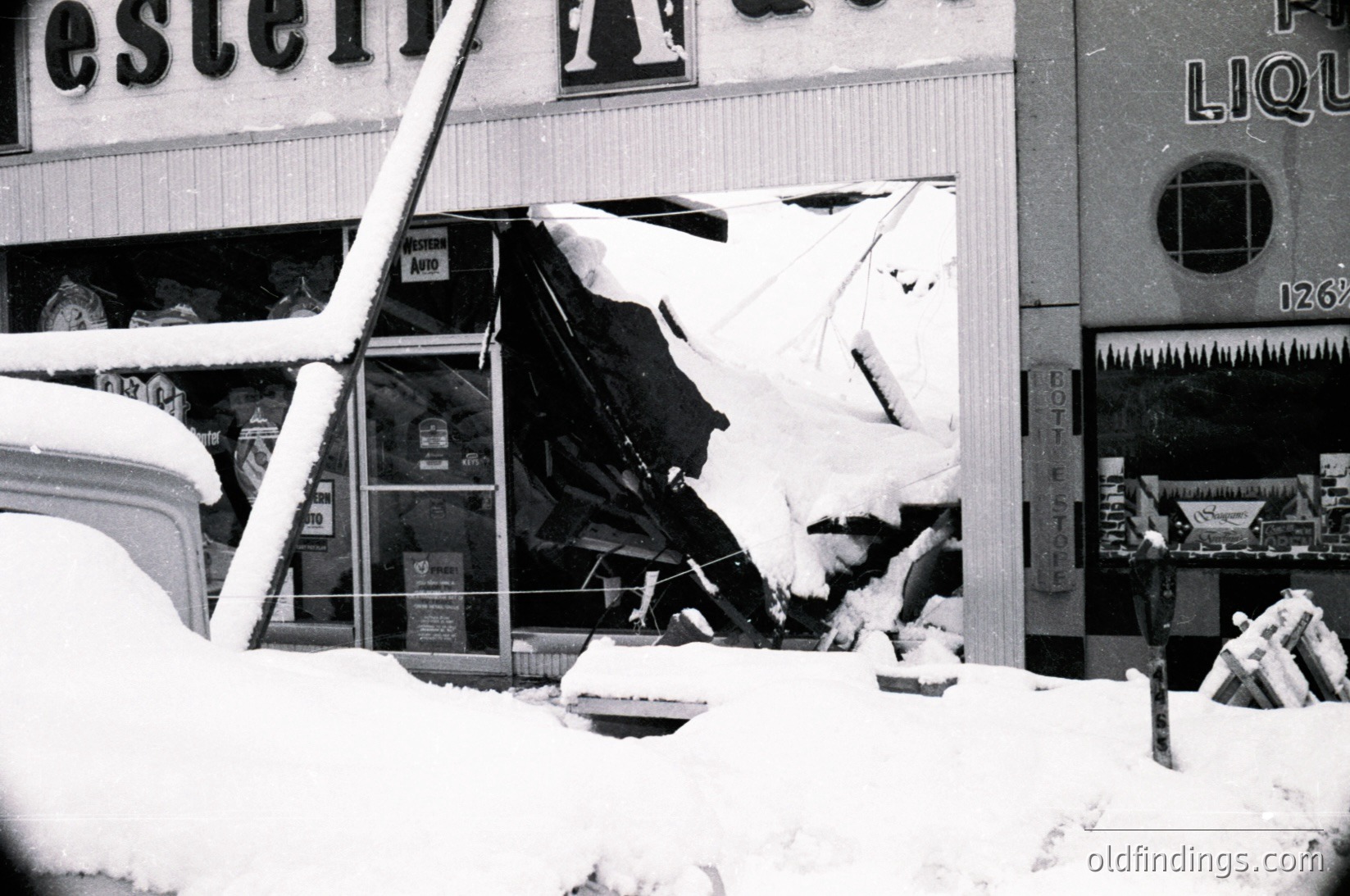 Snow-damaged storefront with collapsed roof and signage reading "Western Auto" and "Pot Liquor." Visible vintage products like aerosol cans and a broken display case. Likely mid-20th century American urban setting.