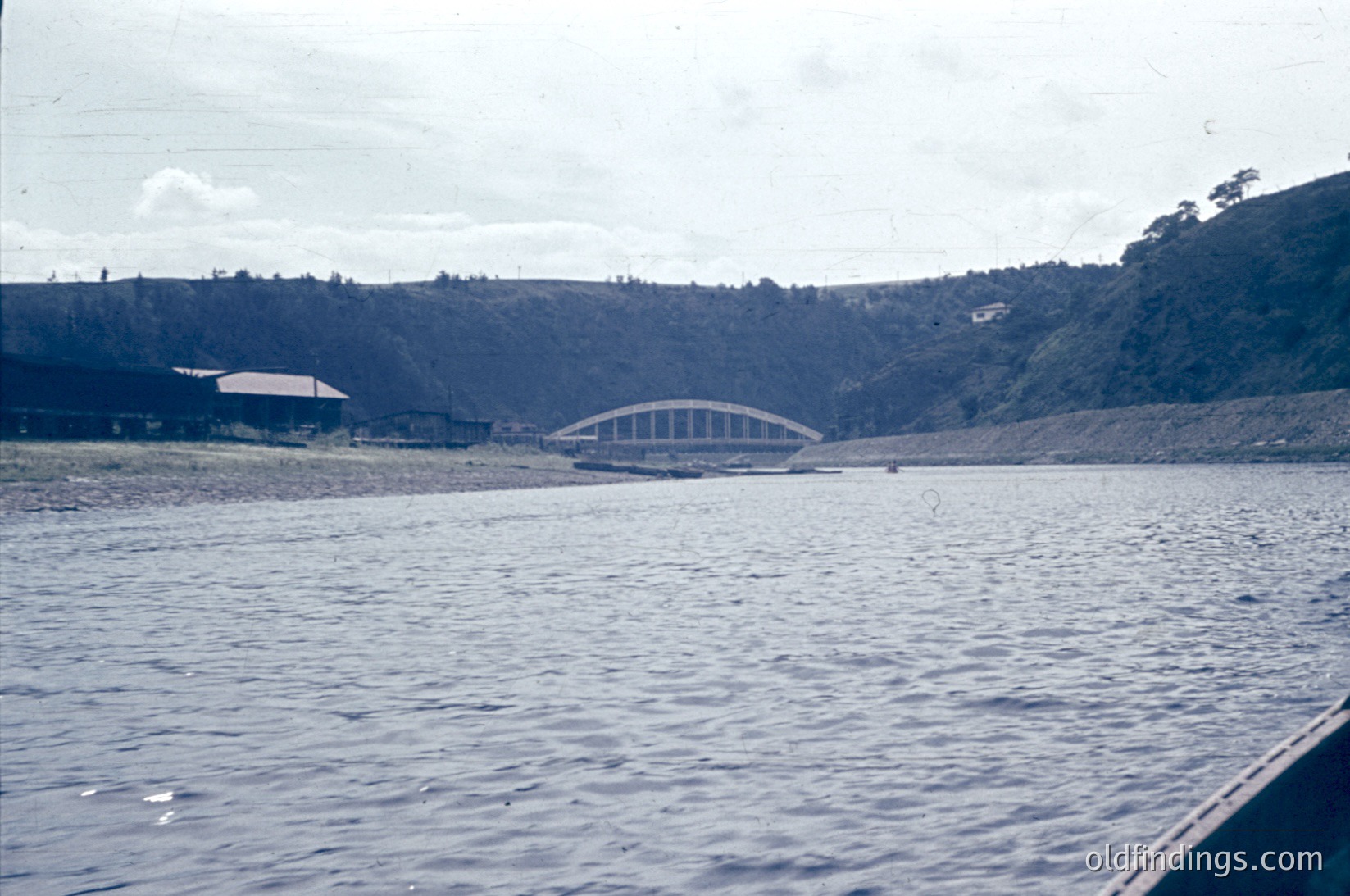 Mid-20th century concrete bridge spanning a reservoir, surrounded by forested hills. Industrial-era infrastructure with minimalist design. Likely Eastern Bloc construction ( ).
