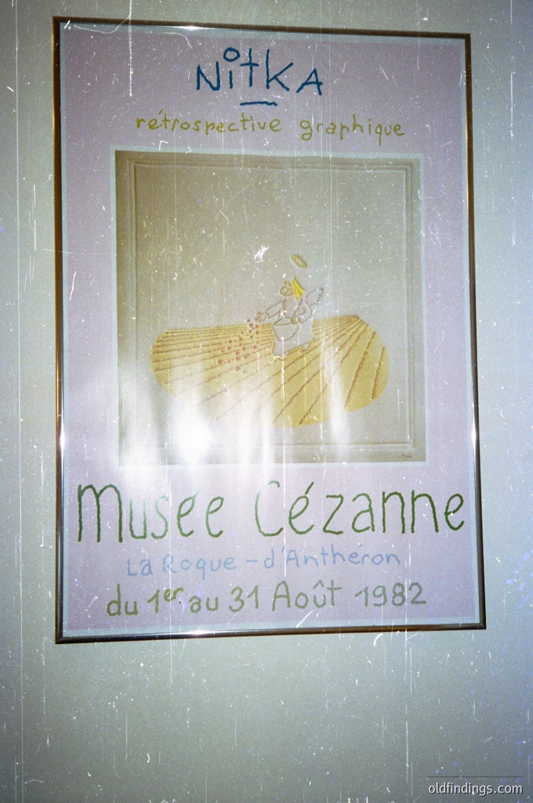 Vintage poster for **Nitka’s retrospective graphic exhibition** at Musée Cézanne, La Roque-d'Anthéron, 1982. Features a stylized illustration of a seated figure with golden wheat motifs. Framed in a classic black border, likely from a mid-century European museum setting. éeCézanne