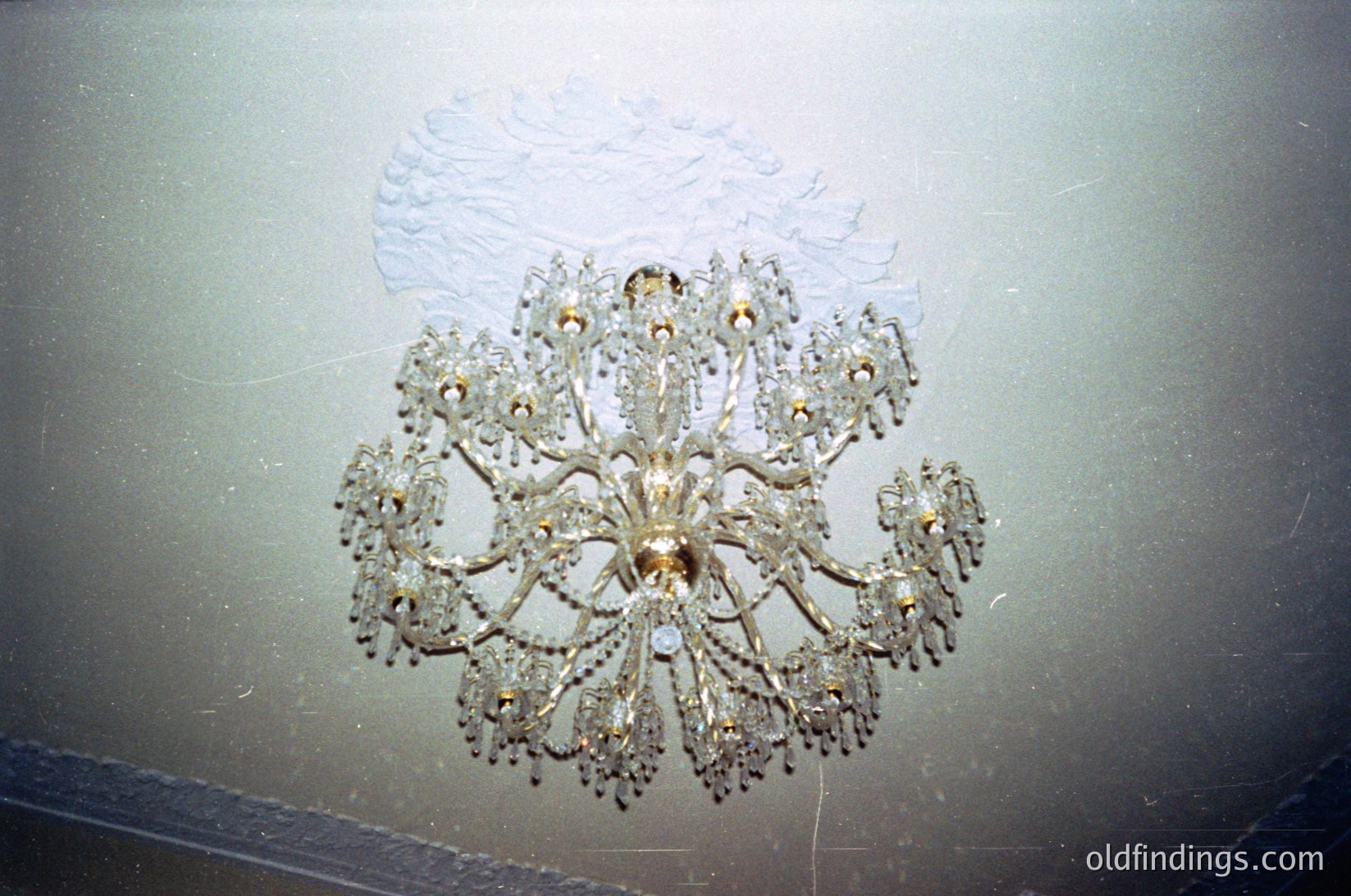 Art deco chandelier with intricate floral metalwork and crystal accents, mounted on a textured ceiling. Likely from mid-20th century (1940s–1960s) interior design.