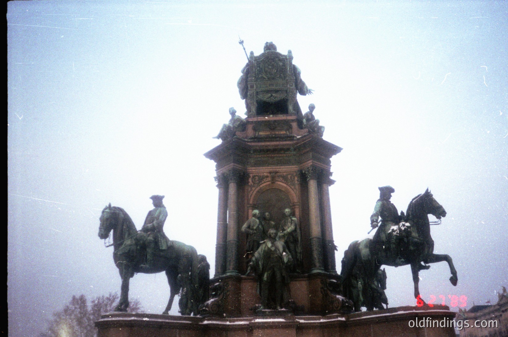 Equestrian monument featuring three mounted figures flanking a central pedestal with ornate reliefs, likely from the late 19th to early 20th century. Architectural style suggests neoclassical or Beaux-Arts influences. Fog obscures background, emphasizing monument’s prominence. Potential historical significance tied to military or civic leaders.