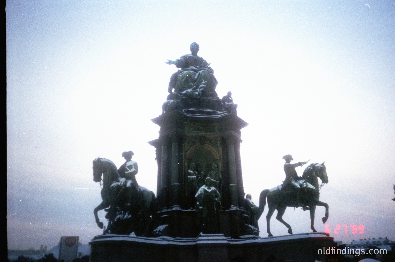 Equestrian monument featuring four life-sized bronze figures atop a stone pedestal, likely from the late 19th to early 20th century. Central figure appears to be a seated historical or military leader, flanked by mounted soldiers in period uniforms. Snow-covered base suggests cold climate. Urban setting with indistinct skyline in background.