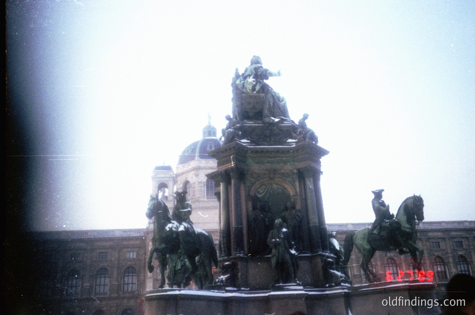 Vintage equestrian monument with four horsemen flanking a central pedestal, set against a grand neoclassical building with domes. Likely Vienna’s **Heldenplatz** (Heroes' Square), featuring the **Victory Column** (1896). Blurred vintage filter enhances nostalgic aesthetic.
