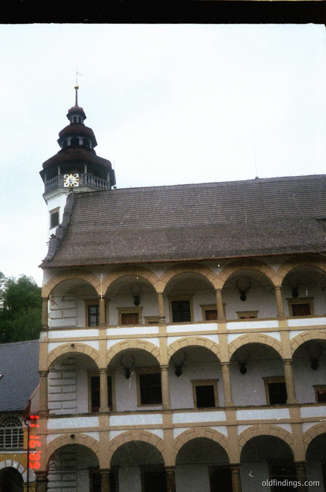 Historic stone building with Renaissance Revival architecture: arched windows and doorways, steep gabled roof with a central clock tower featuring a decorative star emblem. Likely European, 19th-century design.
