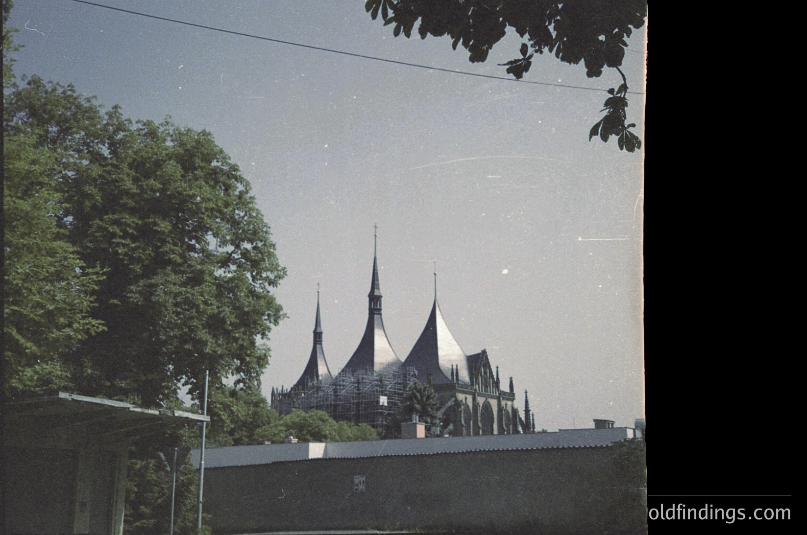 Vintage sepia-toned photo of a distinctive **modernist mosque** with sharp, angular minarets and a sleek, geometric dome. Construction scaffolding suggests mid-20th century (likely 1960s–1970s) in a **Soviet-era urban setting**. Lush greenery frames the scene, contrasting with the industrial aesthetic.