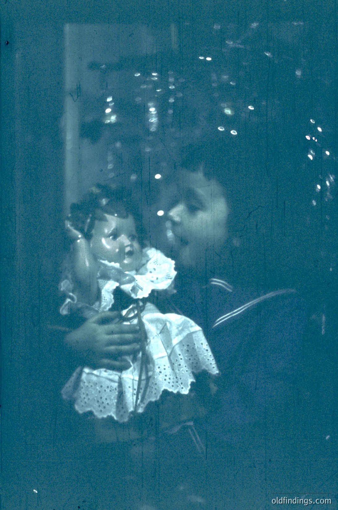 Vintage sepia-toned reflection of a woman holding a child in a patterned dress, captured through a frosted glass window. The scene suggests an indoor setting, likely mid-20th century. The soft focus and lighting evoke nostalgia.