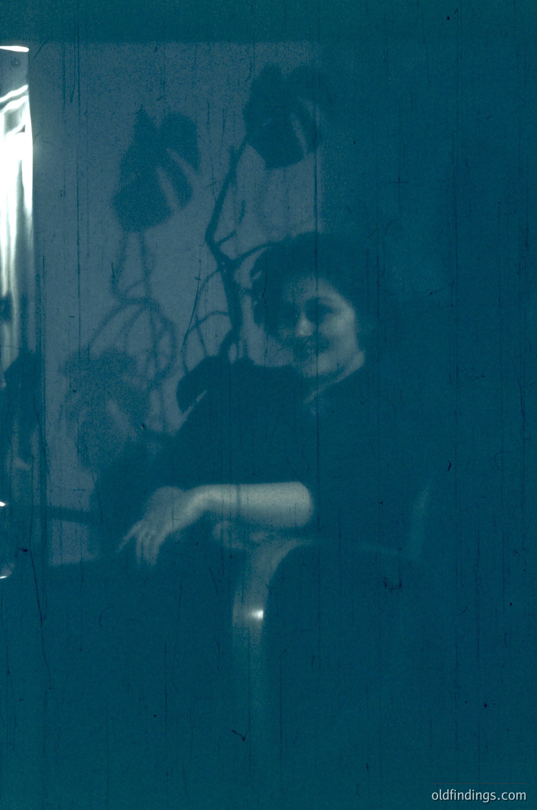 Vintage sepia-toned shadow play on a window, capturing a seated figure with a hat and coat. Light filters through, creating a ghostly silhouette against an interior wall. Likely mid-20th century, evoking nostalgia for analog photography. Ideal for historical research or artistic references.