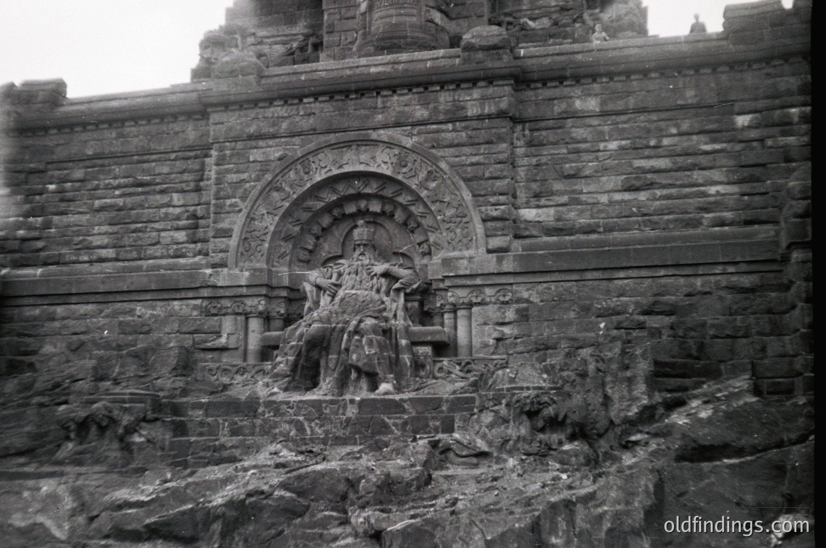 Relief sculpture on weathered stone wall, featuring intricate carvings of seated figures in dynamic poses. Likely part of an ancient temple or monument, showcasing classical stonework and narrative artistry. *(Note: The style and carving technique suggest Southeast Asian, possibly Borobudur or similar 7th–9th century temple complex.)*