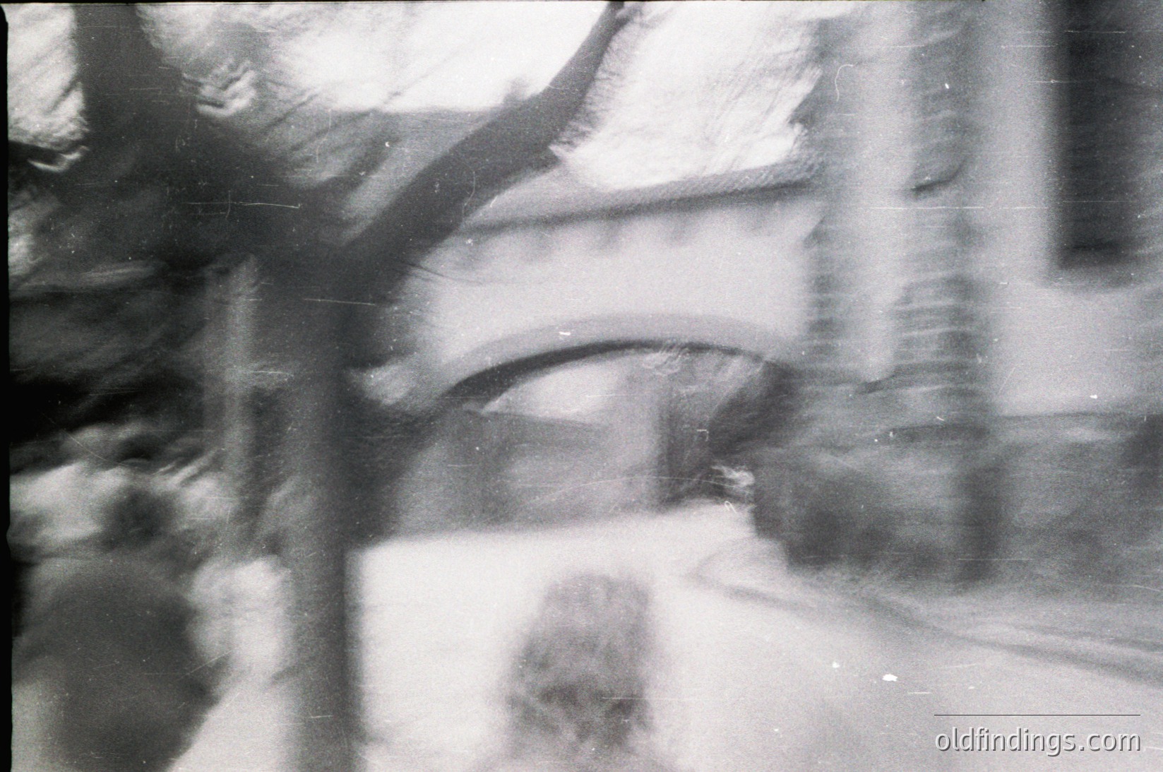 Vintage monochrome shot of blurred architectural details—likely a curved balcony or overhang with visible concrete edges and shadowed textures. Motion blur suggests dynamic urban life, possibly from a moving vehicle or handheld camera.