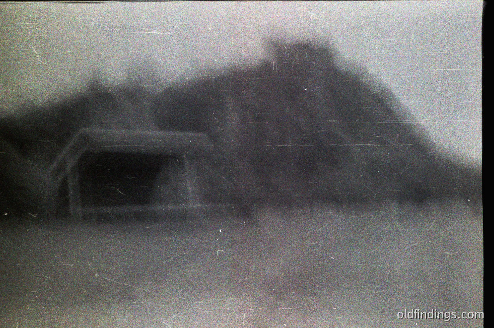 Vintage sepia-toned photo of a fortified bunker-like structure with a sloped roof and entrance tunnel, likely mid-20th century. Blurred details suggest wartime or military architecture.