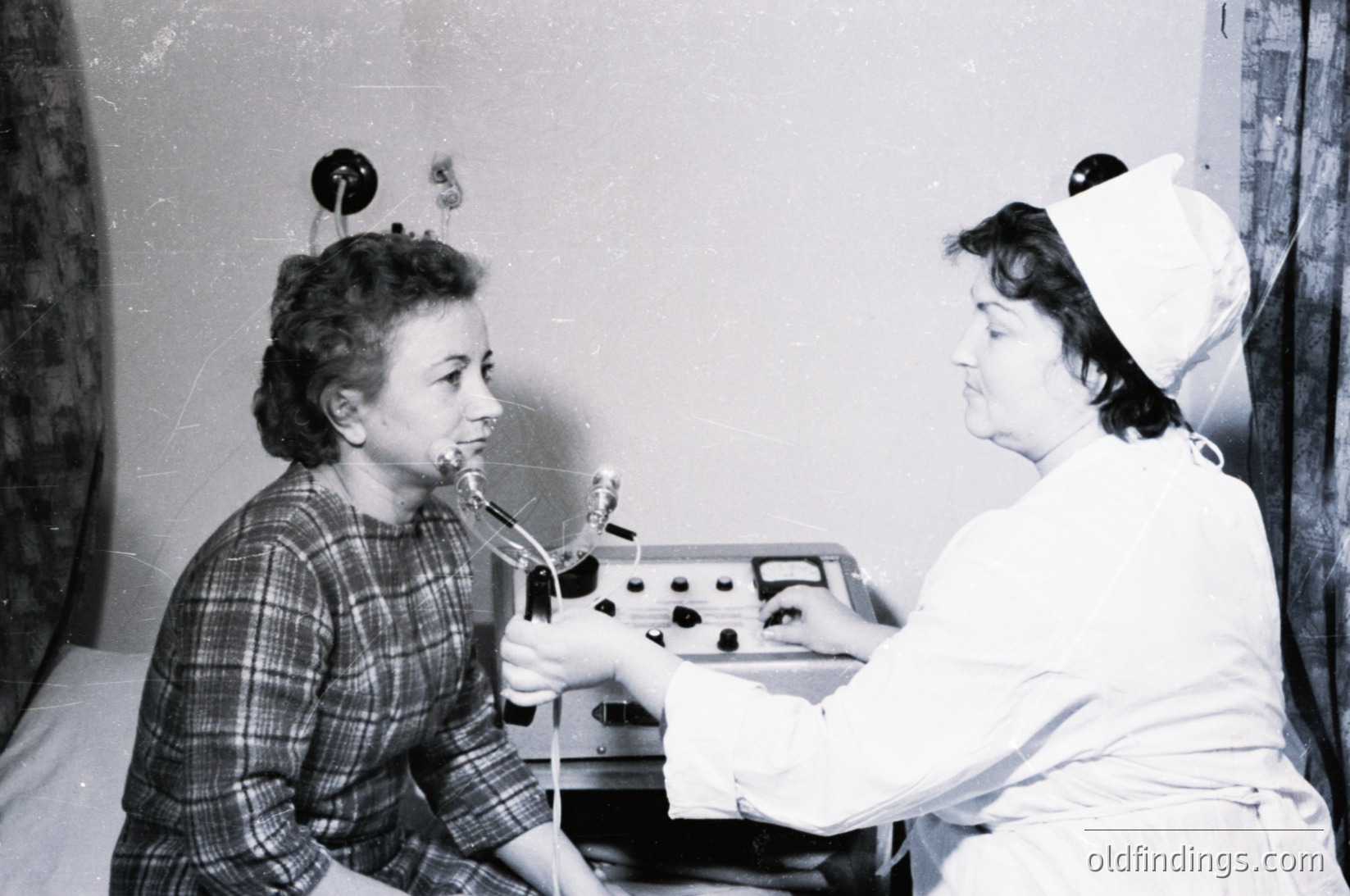 Mid-20th century dental clinic scene: patient seated in chair receiving treatment with early electric dental drill. Nurse in white cap and uniform assists, holding dental tools. Plaid blouse and vintage office decor suggest 1950s–1960s setting.