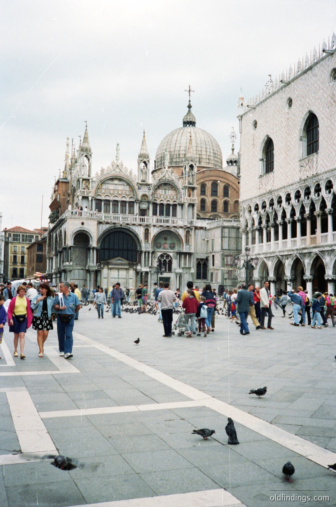 St. Mark’s Square (*Piazza San Marco*) in Venice, Italy, showcasing the iconic **Doge’s Palace** with its Gothic façade and central dome. Crowds of tourists and pigeons populate the broad marble plaza, framed by historic Venetian architecture. Likely captured in the late 20th century.