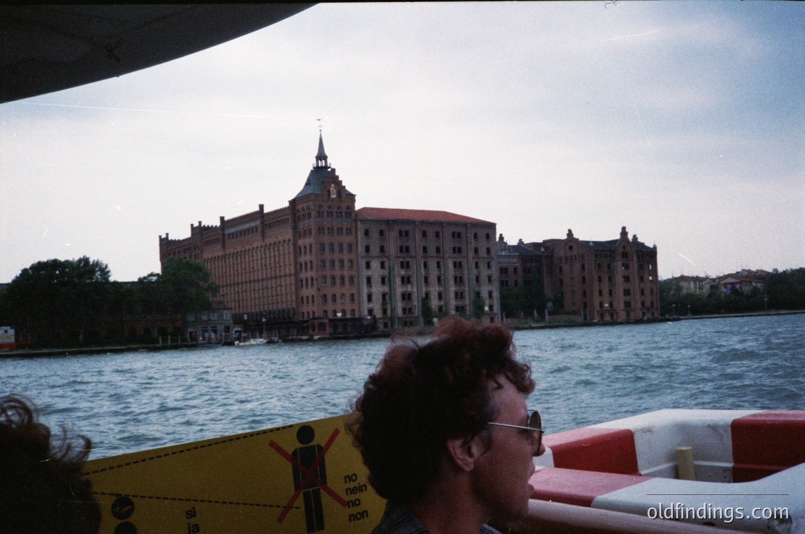 Historic waterfront building with Art Deco tower, likely a former warehouse or grain elevator. Prominent "no entry" sign in foreground. Mid-20th century urban river scene.