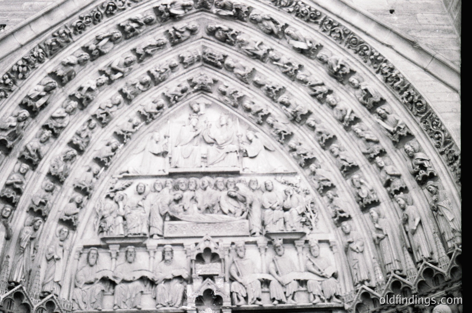Gothic stone portal featuring intricate high-relief sculptures depicting biblical scenes, likely from a 13th–14th century European cathedral. Central figures include Christ in Majesty flanked by apostles and angels, with lower tiers showing prophets and donors. Architectural details include pointed arches and tracery.