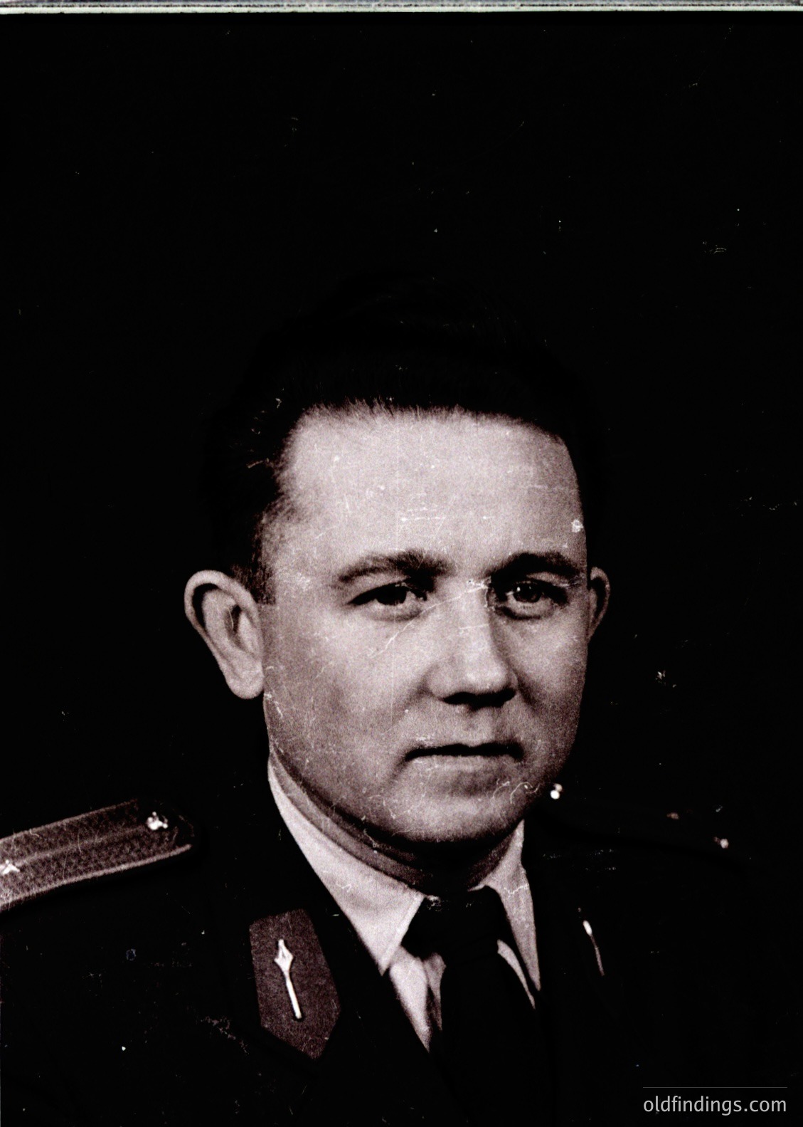 Portrait of a man in a formal military uniform with epaulettes, likely from the mid-20th century. Dark, serious expression with short hair and a tie. Background suggests a studio setting.
