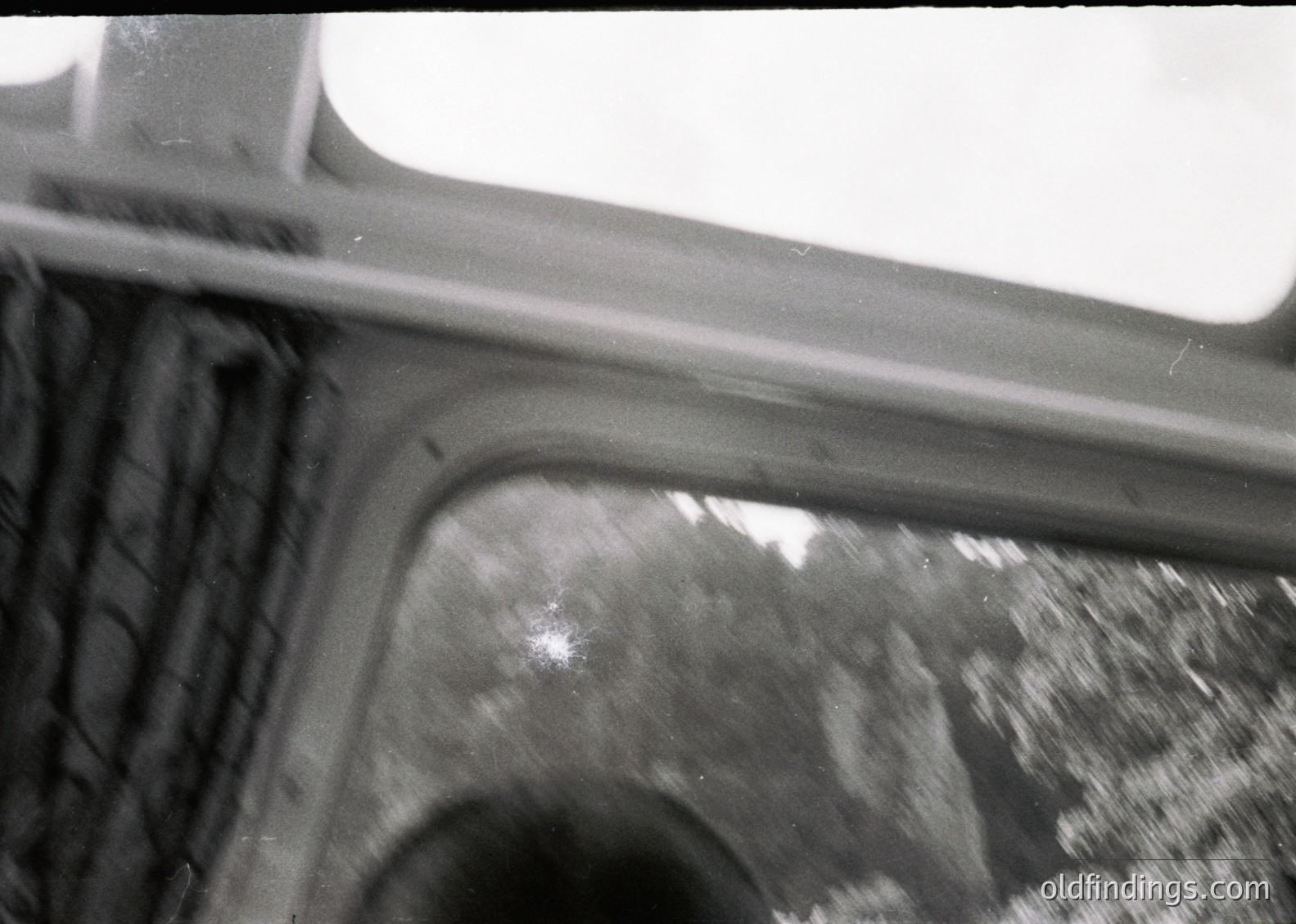 Close-up of a vintage car’s rearview mirror and door frame, showing wear and motion blur. Likely mid-20th century automotive design, suggesting classic or retro styling.