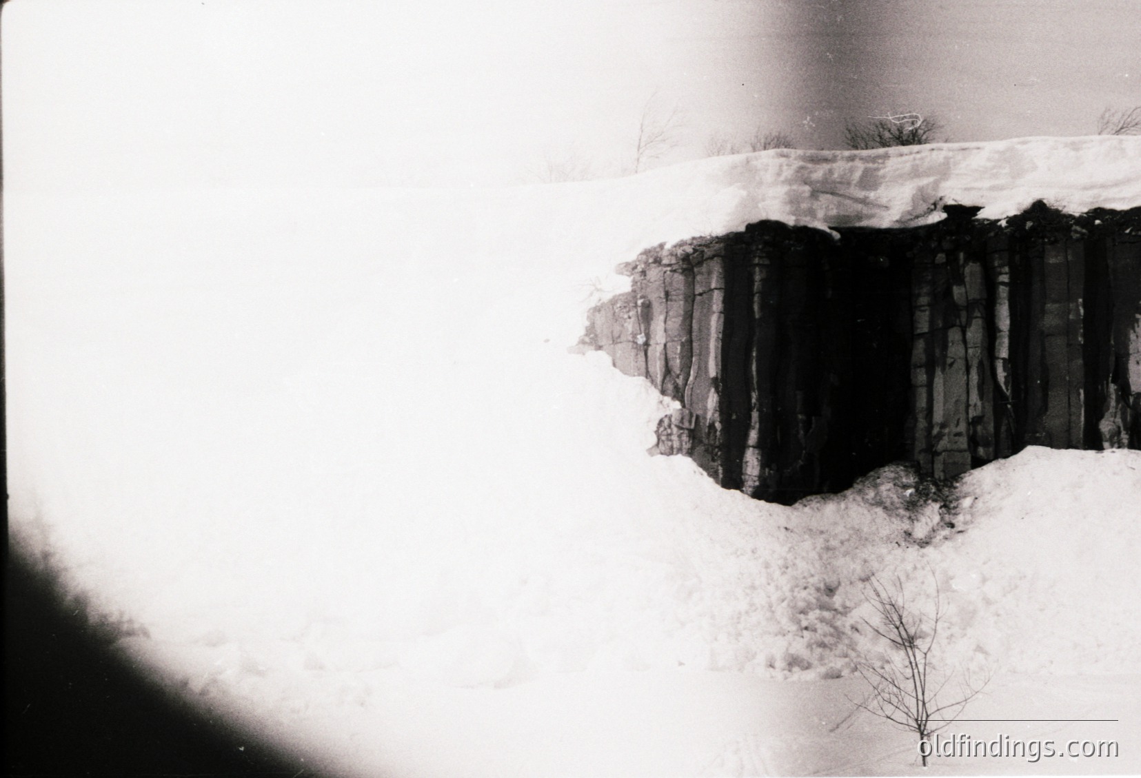 Black-and-white aerial view of a snow-covered cliffside with stacked wooden planks, likely for erosion control or construction. Minimal vegetation visible. Style suggests mid-20th century engineering documentation.