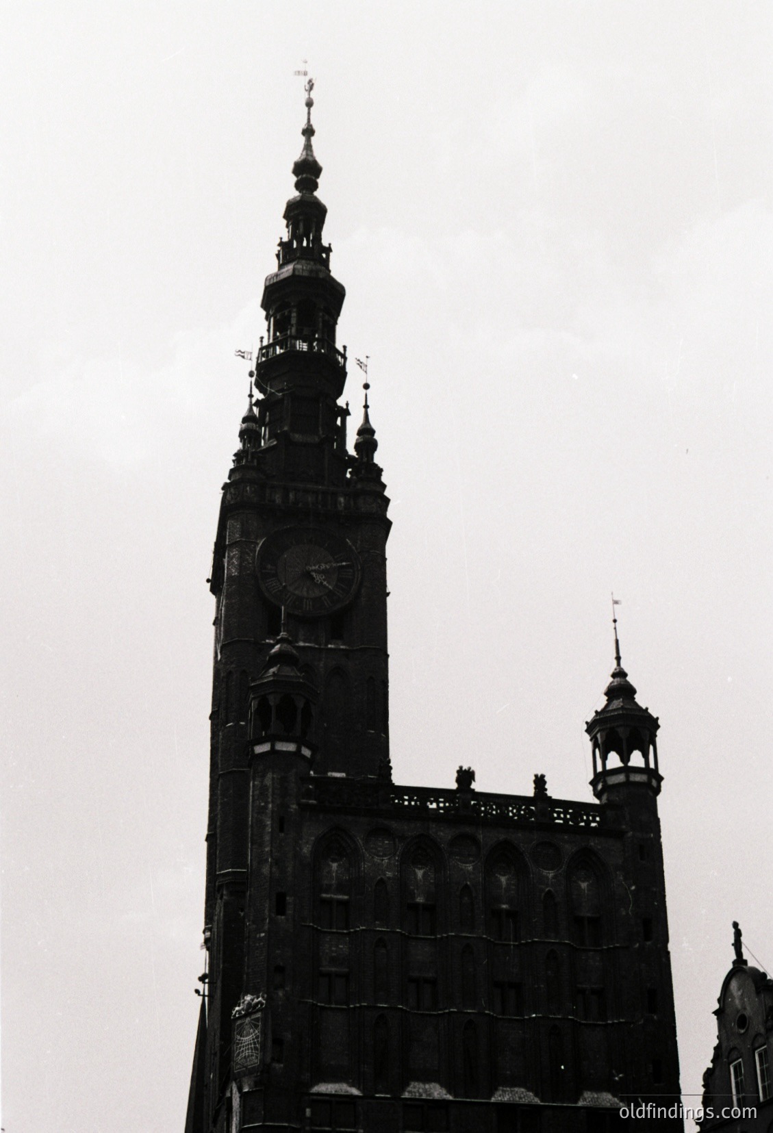 Gothic-style clock tower with ornate spire and intricate stonework, likely part of a historic European cathedral. Symmetrical facade features a large clock near the top and decorative arches below. Architectural details suggest 14th–16th century construction.