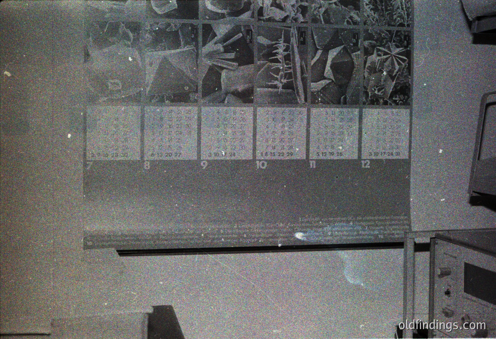 Vintage slide carousel with 12 labeled slides (8–12) featuring black-and-white nature/landscape imagery. Below, a handwritten note on a transparent sheet. Office setting with typewriter and desk. Likely mid-20th century.