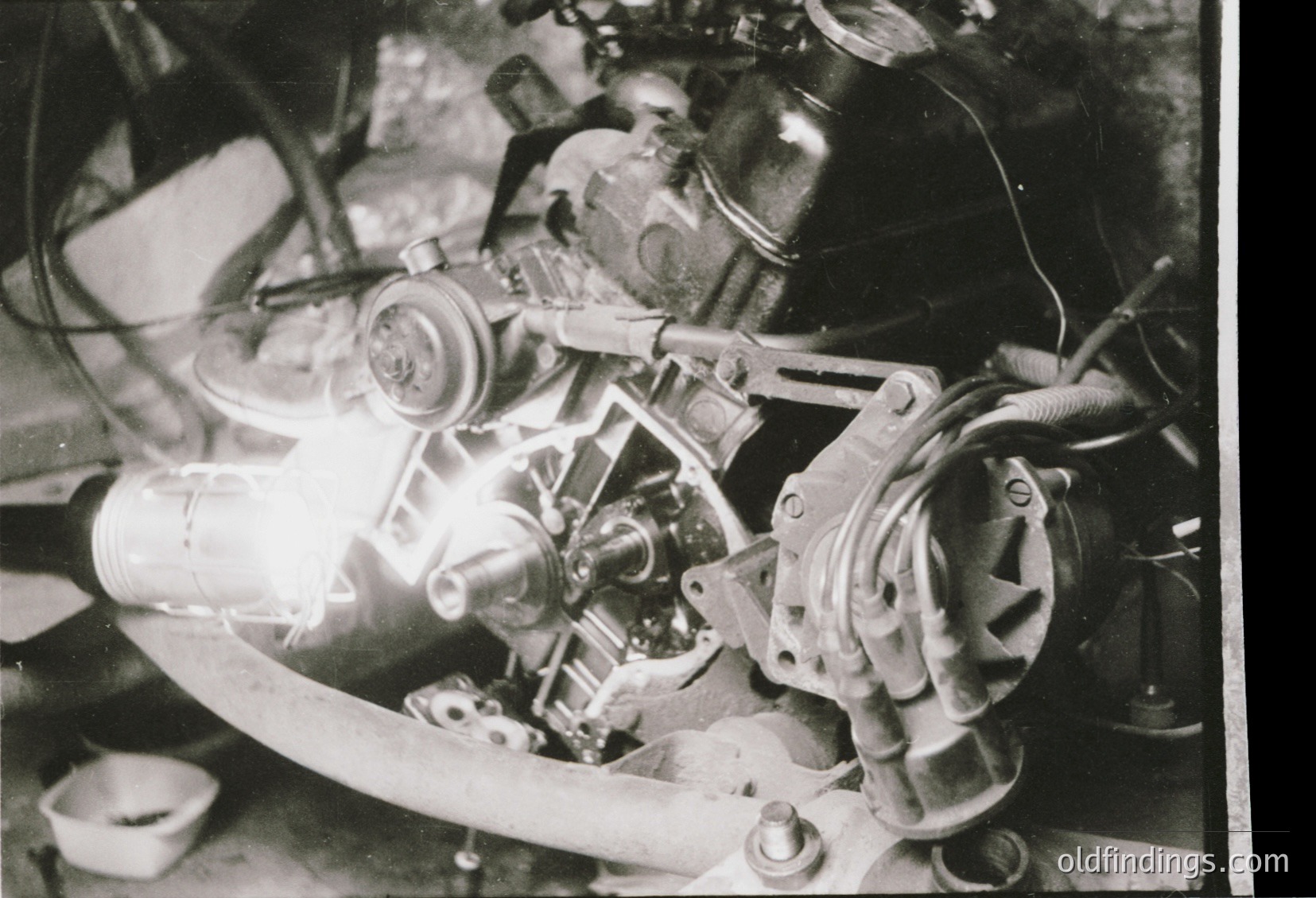 Close-up of a vintage motorcycle engine with exposed valve train, carburetor, and flywheel—likely a classic British or European model from the 1950s–60s. Distinctive pressed-steel construction and manual choke lever visible.
