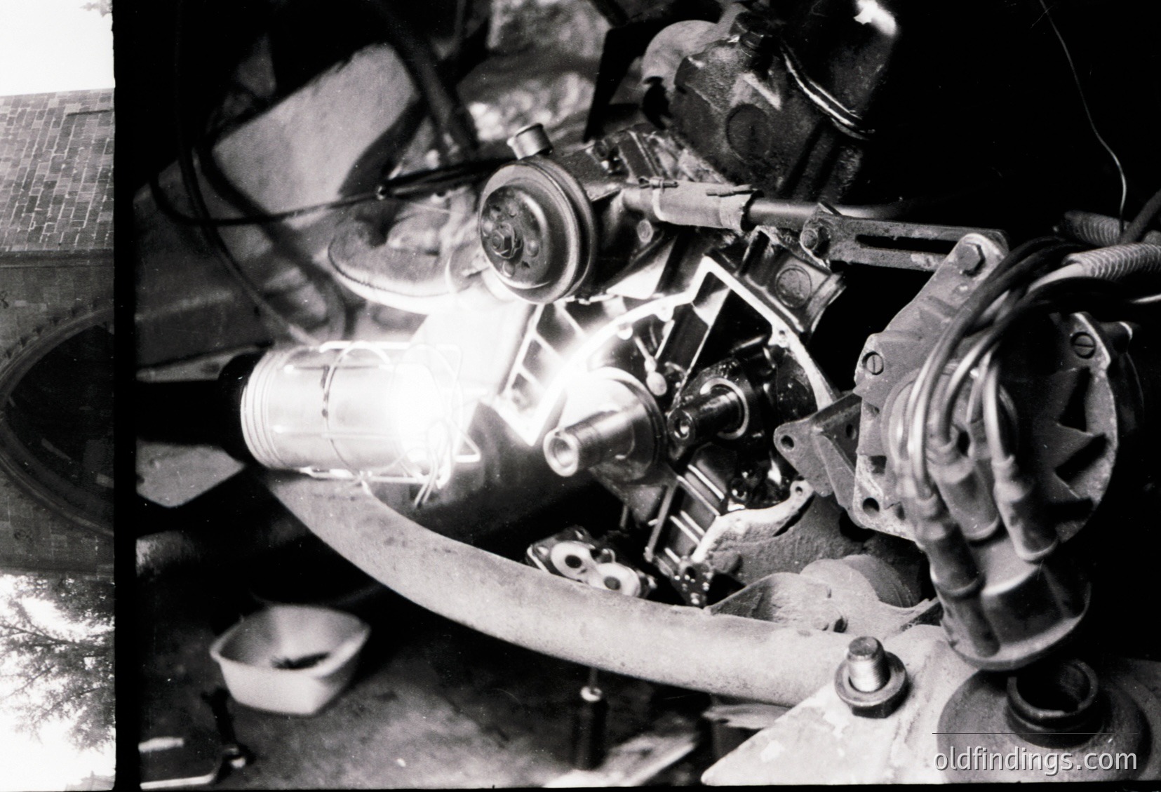 Close-up of a vintage motorcycle engine with exposed valve train, carburetor, and flywheel. Distinctive dual overhead valves and chain-driven camshaft visible. Likely mid-20th century European design.