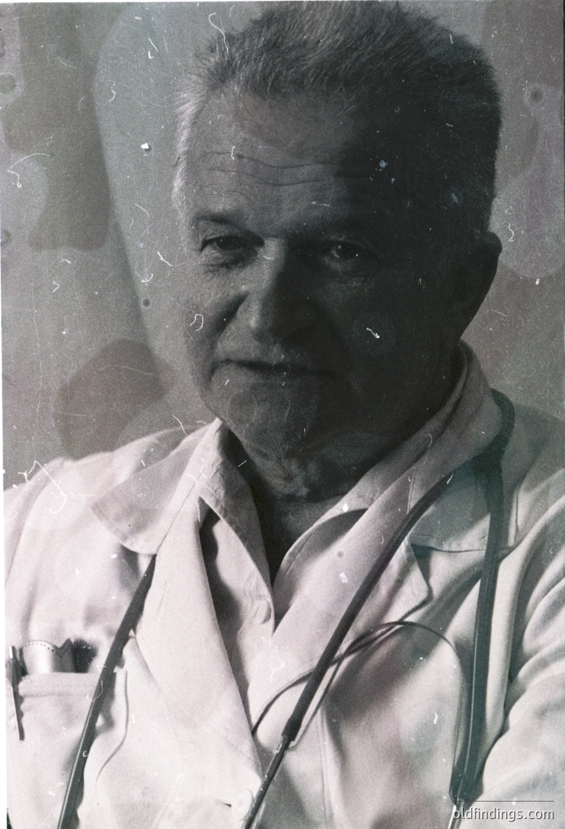 Portrait of an elderly man in a white lab coat, likely a doctor, with stethoscope draped around his neck. The vintage sepia tone suggests a mid-20th century setting, possibly or . The image evokes themes of medical history and professional attire.