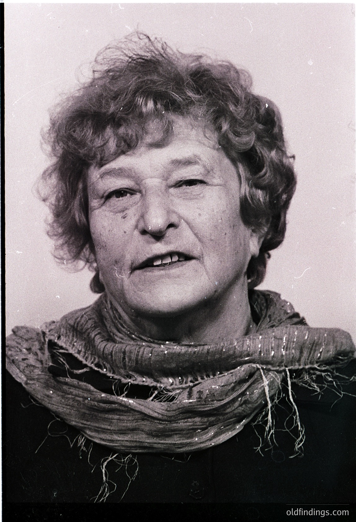 Portrait of an elderly woman in mid-profile, wearing a textured scarf. Mid-20th century style with matte black background. Likely professional or documentary photography.