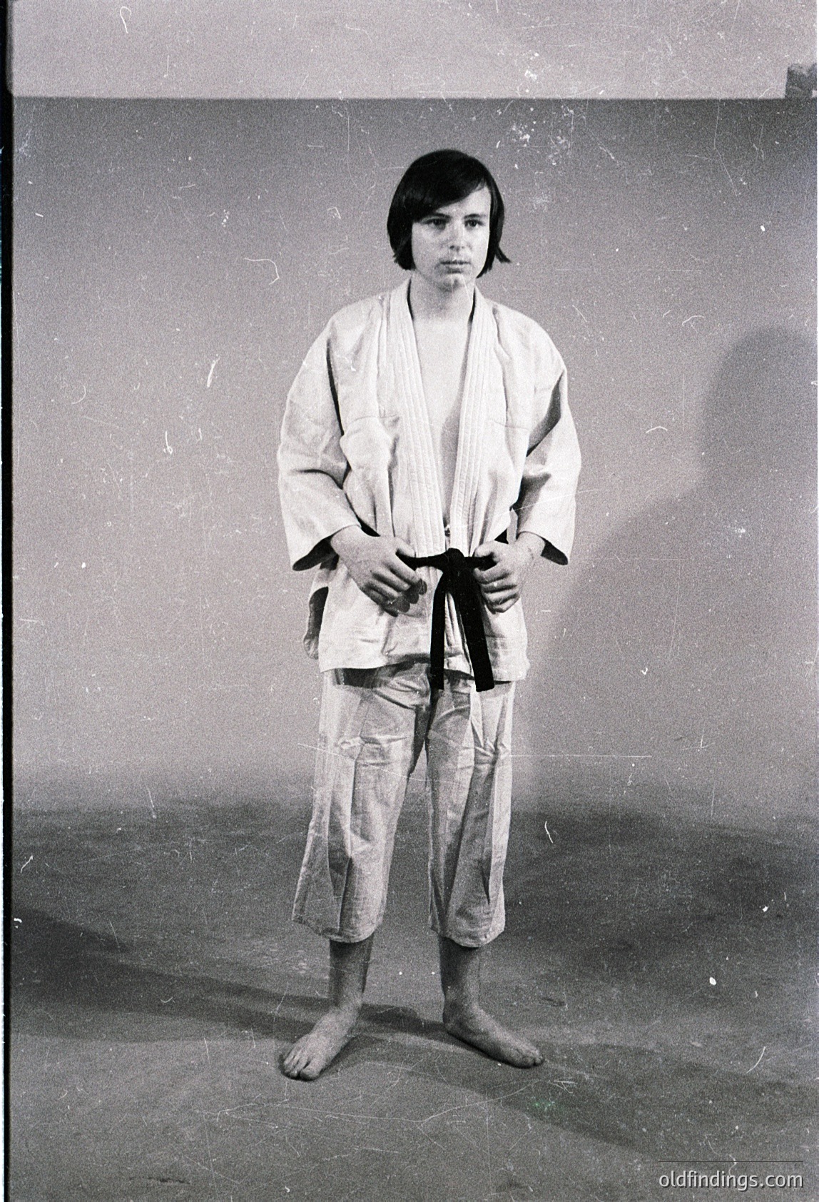 Portrait of an individual in a traditional **karate gi** (white jacket and pants with a black belt), standing in a neutral indoor setting. The belt suggests a rank of **black belt** or higher. Style and attire indicate **Japanese martial arts** influence, likely mid-to-late **20th century**.