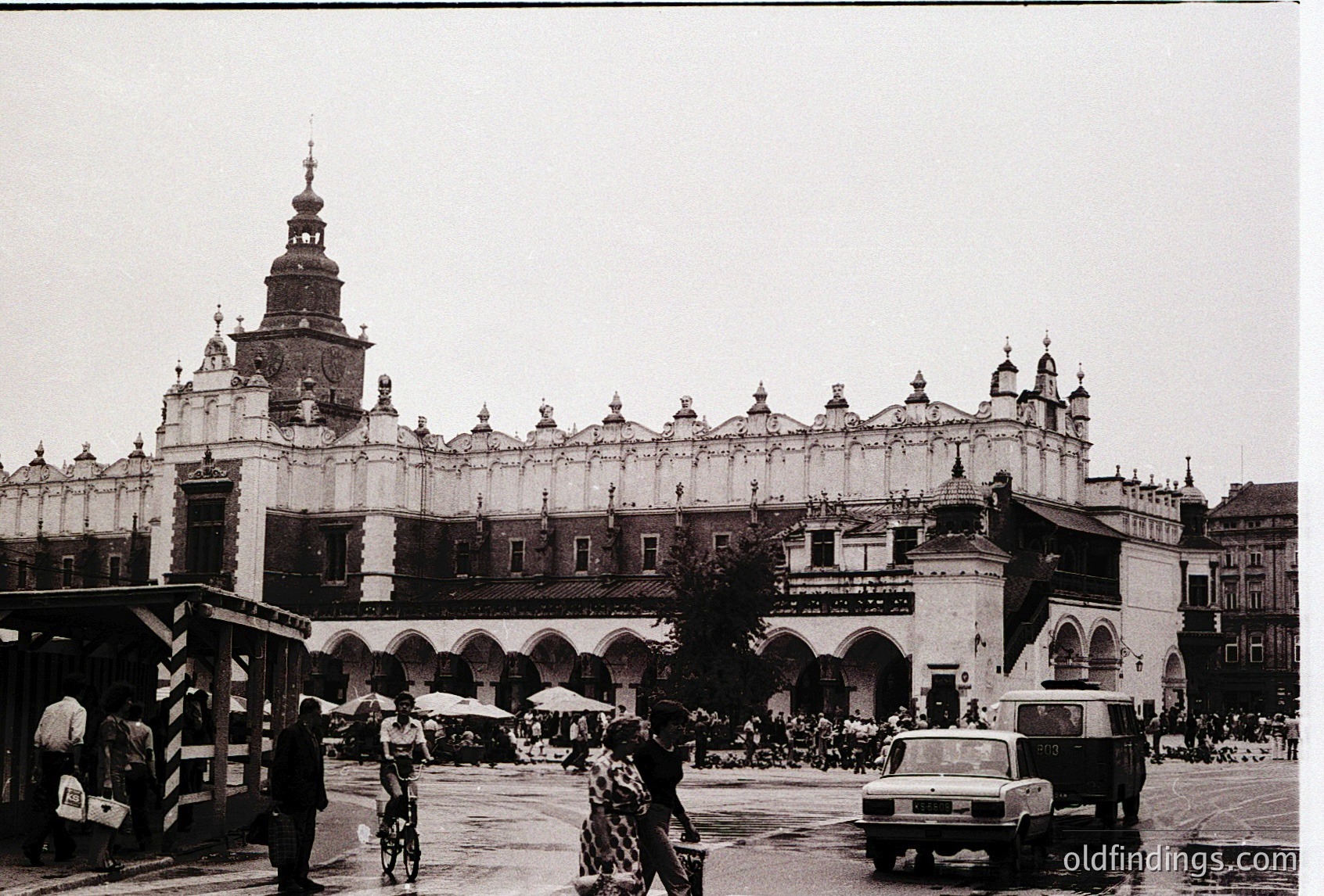 Historic **Wawel Royal Castle** in Kraków, Poland, showcasing its iconic **Renaissance-Gothic architecture** with arched colonnades and a central tower. Mid-20th century street scene with vintage vehicles and pedestrians.