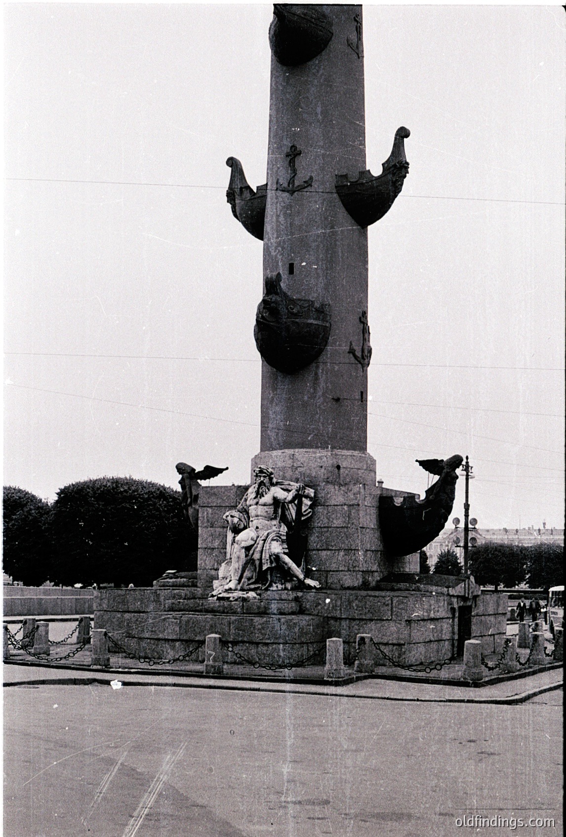 Monumental column with sculpted figures depicting maritime labor—seamen hauling ropes and anchors. Base features a dynamic group of workers in mid-effort. Likely 19th–early 20th century maritime tribute. Urban setting with distant cityscape.